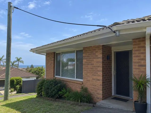 Brick home with overhead service cable attached to a roof bracket and pole in Collaroy